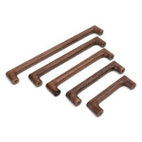 Cinq poignées Salgado Walnut de yessential.fr, chacune avec un design élégant et moderne et des coins arrondis, sont placées en diagonale sur une surface blanche. Des trous de vis visibles accentuent les différentes longueurs de ces manches en bois.