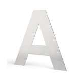 L'Adamo Stainless Steel 15cm de yessential.fr est une lettre majuscule verticale en métal avec une finition lisse et brossée, sur un fond blanc uni et avec une ombre subtile.