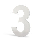 Un grand chiffre 3 métallique avec une finition argent brossé se tient debout sur un fond blanc. Cet élégant numéro de maison Animo en acier inoxydable de 15 cm (sans perçage) de yessential.fr est parfait pour les maisons contemporaines.