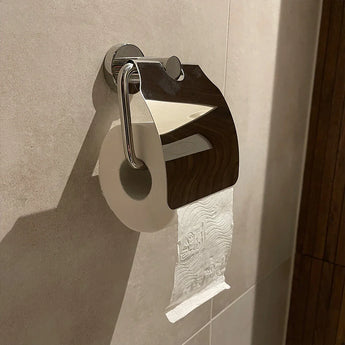 Un rouleau de papier toilette est suspendu au porte-rouleau de papier toilette Julio Chrome avec couvercle de yessential.fr, le couvercle brillant reflète la salle de bain carrelée et rehausse le look moderne avec des accessoires de toilette élégants.