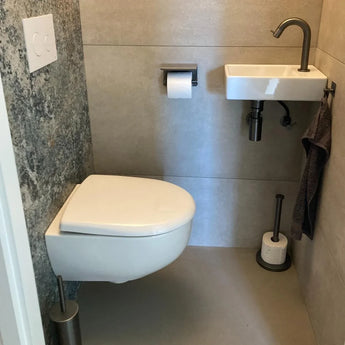 Une petite salle de bains moderne avec des toilettes murales, un lavabo blanc compact avec un robinet gris et l'élégant ensemble de WC Juano Gunmetal (sans perçage) de yessential.fr soigneusement agencé pour plus de commodité.