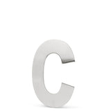 L'Adamo en acier inoxydable 15 cm de yessential.fr est un C majuscule métallique avec une finition argent brossé, debout sur un fond blanc uni - idéal pour ajouter une élégance moderne à l'adresse de votre maison.