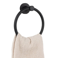 Une texture de serviette beige est suspendue au-dessus des serviettes Elarbo Black de yessential.fr, fixées sur un mur blanc - une solution élégante et encombrante pour toute la salle de bain.
