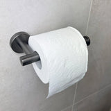 Un rouleau de papier toilette blanc avec un subtil motif en relief est monté sur le porte-rouleau de papier toilette Tino Gunmetal de yessential.fr, ajoutant du style au mur carrelé gris clair et complétant d'autres accessoires de toilette.