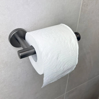 Un rouleau de papier toilette blanc avec un subtil motif en relief est monté sur le porte-rouleau de papier toilette Tino Gunmetal de yessential.fr, ajoutant du style au mur carrelé gris clair et complétant d'autres accessoires de toilette.