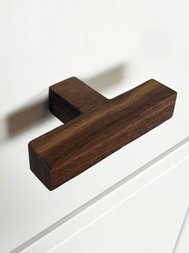 Le bouton Vigio Walnut de yessential.fr est installé sur une façade d'armoire blanche avec des détails de panneau simples.