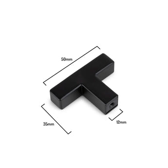 Le bouton noir Vigio de yessential.fr est un bouton de meuble moderne en forme de T (50 mm de large, 35 mm de haut, 12 mm d'épaisseur), représenté sur un fond blanc. Fait partie de la collection Vigio et idéale comme poignée de placard contemporaine.