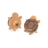 Les boutons de meubles Bambino Turtle de yessential.fr sont des boutons de tortue en bois avec un revêtement foncé et une tête et des pieds clairs, idéaux pour la chambre des enfants. Un bouton montre l'avant, l'autre l'arrière avec montage à vis.