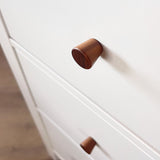 Gros plan d'une armoire de couleur claire avec des boutons en noyer Salgado de yessential.fr. L'accent est mis sur le bouton rond supérieur, avec un autre en dessous.