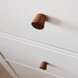 Gros plan de deux boutons en noyer Salgado de yessential.fr sur une armoire blanche, avec un bouton au point et l'autre légèrement flou en arrière-plan.