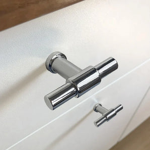 Gros plan du bouton 10x Cordero Chrome de yessential.fr monté sur un boîtier blanc : un bouton est net, l'autre flou. Un choix idéal pour les intérieurs modernes à la recherche de boutons de meubles chromés élégants.