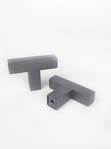Deux boutons Vigio Gunmetal de yessential.fr sont présentés sur un fond blanc - un droit et un posé à plat, exposant les rayures. Les deux ont une finition lisse et mate qui met en valeur leur design moderne.