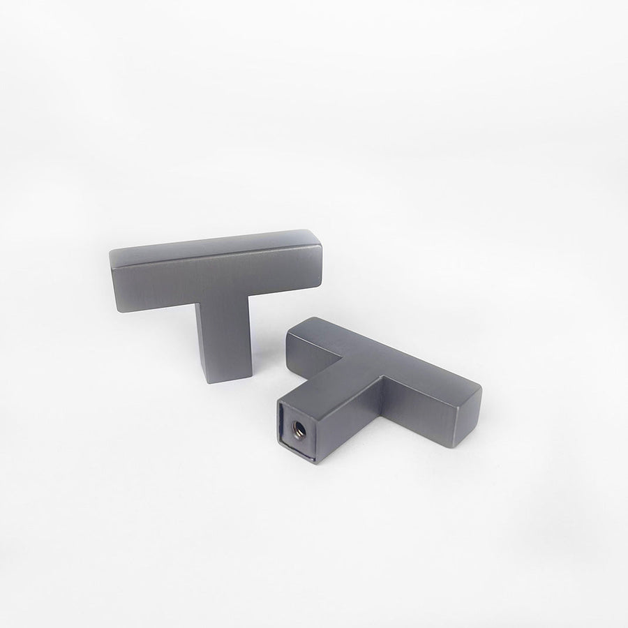 Deux boutons Vigio Gunmetal de yessential.fr sont présentés sur un fond blanc - un droit et un posé à plat, exposant les rayures. Les deux ont une finition lisse et mate qui met en valeur leur design moderne.
