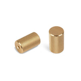 Deux boutons Remo Gold Deluxe de yessential.fr - une paire de boutons cylindriques en laiton avec des surfaces moletées texturées, l'un avec un trou et l'autre vertical avec un dessus lisse - présentés sur fond blanc.