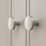 Deux boutons de meubles en acier inoxydable Marizo en métal brossé de yessential.fr sont montés sur des portes d'armoires de couleur claire, qui, en gros plan, soulignent leur design moderne et minimaliste.