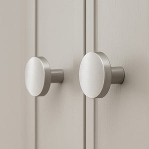 Deux boutons de meubles en acier inoxydable Marizo en métal brossé de yessential.fr sont montés sur des portes d'armoires de couleur claire, qui, en gros plan, soulignent leur design moderne et minimaliste.