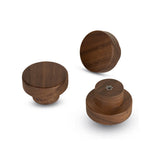Trois boutons Arriero Walnut de yessential.fr sont présentés sur un fond blanc sous différents angles, mettant en valeur leur finition lisse et leur grain de bois. Un bouton montre la borne à vis visible à l'arrière.