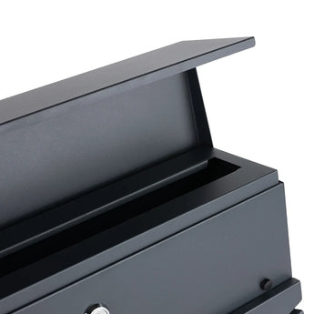 Un gros plan de la boîte aux lettres Sergio Anthracite de yessential.fr montre le couvercle partiellement ouvert, révélant l'intérieur. Cette boîte aux lettres moderne a un design simple et élégant avec une petite serrure argentée sur le devant.