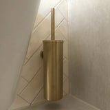 L'ensemble Armando Gold de yessential.fr se compose d'une brosse de toilette dorée avec un support cylindrique assorti. Monté dans le coin, il se démarque des carreaux muraux blancs disposés en diagonale pour un look élégant.