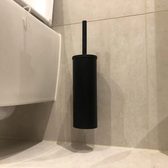 L'Ensemble WC Romano Noir de yessential.fr, avec une finition WC noir mat avec support, est monté sur un carrelé beige avec toilettes blanches, qui est une combinaison élégante et raffinée de l'ensemble d'accessoires de la salle de bain.