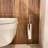 Des toilettes suspendues blanches modernes sont associées à l'ensemble de toilettes Romano Chrome de yessential.fr, contre un mur vertical avec des panneaux en bois et un sol carrelé de couleur claire.