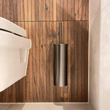 Une salle de bains moderne sur la gauche présente des toilettes blanches et l'ensemble de toilettes yessential.fr Romano Gunmetal monté sur des panneaux de bois verticaux, complétés par des carreaux de sol clairs pour un look minimaliste.
