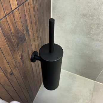 Monté sur un mur lambrissé en bois aux côtés de carrelage clair et d'un sol carrelé, l'ensemble WC Cosimo Black de yessential.fr ajoute une touche élégante à vos accessoires de salle de bain.