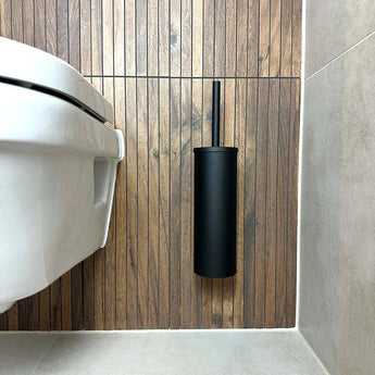 L'ensemble WC Cosimo Black de yessential.fr est monté sur un mur en bois à côté de toilettes blanches dans une salle de bain moderne avec carrelage gris et carrelage mural beige clair - une élégante mise à niveau d'accessoire de salle de bain.
