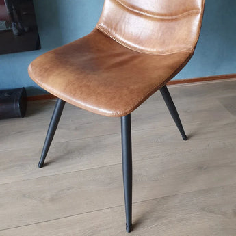 Une méridienne et un marron avec un bord incurvé et des bords en métal noir, équipés de hottes anti-rayonne Paco Set Ø 12-16 mm yessential.fr, avec une robe sur parquet et une couleur blanche sur le mur.