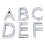 Six lettres majuscules 3D chromées de 60 mm - A, B, C, D, E et F - de la série Silvio Chrome de yessential.fr sont disposées en deux rangées sur un fond blanc et ressemblent à des chiffres collants avec une couche adhésive.