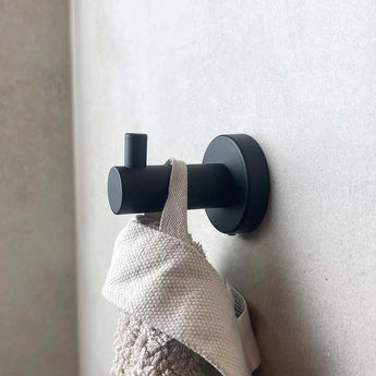 Doté d'un design cylindrique moderne, le crochet noir Justo de yessential.fr maintient une serviette beige texture avec un clair, ajoutant à la fois style et fonctionnalité à votre salle de bain.