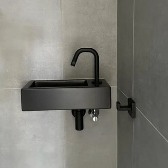 Un évier rectangulaire noir moderne avec robinet assorti est monté sur un mur carrelé gris, à côté du crochet Valo Black Hook de yessential.fr pour une élégance subtile.