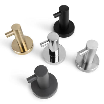 Cinq distributeurs de savon cylindriques en or, noir, chrome, argent brossé et gris mat sont exposés sur fond blanc. Combinez-les avec le crochet porte-serviettes de salle de bain assorti ou le crochet Justo Chrome de yessential.fr pour une touche élégante.