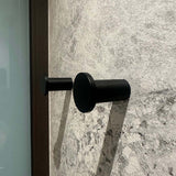 Quatre crochets à serviettes cylindriques noirs Carreno de yessential.fr, en acier inoxydable, sont montés sur un mur texturé en pierre grise - un accessoire de salle de bain élégant et moderne.