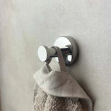 Le crochet Kyano Chrome de yessential.fr, au design cylindrique et à la finition brillante, utilise principalement une texture serviette beige sur fond gris clair - il est donc élégant et prêt à être importé du bain.