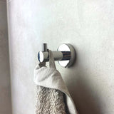 L'ensemble de toilettes Lorenzo Chrome de yessential.fr contient une serviette beige et un chiffon gris sur un mur carrelé de couleur claire et ajoute une fonctionnalité élégante à votre salle de bain.