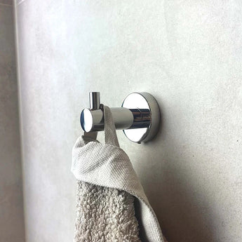 L'ensemble de toilettes Lorenzo Chrome de yessential.fr contient une serviette beige et un chiffon gris sur un mur carrelé de couleur claire et ajoute une fonctionnalité élégante à votre salle de bain.