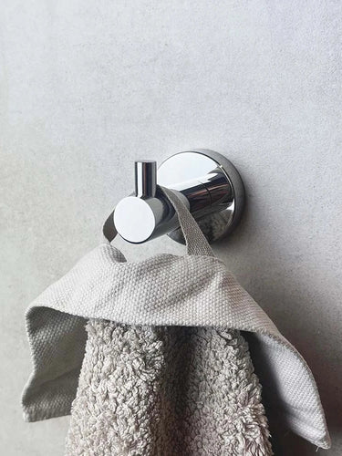 Une serviette texturée grise est suspendue au crochet Justo Chrome de yessential.fr, monté sur un mur lisse gris clair.