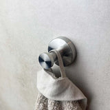 L'ensemble de toilettes en acier inoxydable de yessential.fr est composé d'une fresque murale au crochet et en acier inoxydable brossé au design moderne, présenté avec une serviette beige et une boucle avec un gris clair.