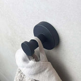 Gros plan sur l'ensemble WC Santino Black de yessential.fr monté sur un mur clair, qui accueille une serviette avec une boucle en tissu et ajoute un style moderne à vos accessoires de salle de bain.