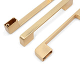 Trois poignées Ramiro Gold Deluxe de yessential.fr se trouvent sur un fond blanc, deux plates et une inclinée pour montrer le trou de montage.