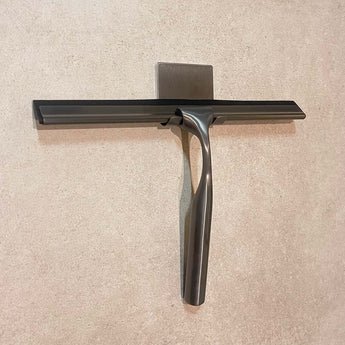 Un Zamoro Gunmetal de yessential.fr repose sur le sol carrelé, sa poignée en acier inoxydable brillant à la lumière.