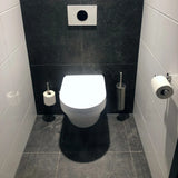 Une salle de bains moderne comprend des toilettes murales blanches, des murs et des sols carrelés foncés et l'ensemble de toilettes en acier inoxydable yessential.fr Xavo : une élégante brosse de toilettes en acier inoxydable avec support, un rouleau de papier toilette monté et un rouleau supplémentaire au sol.