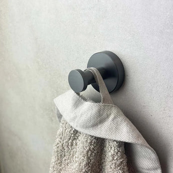 Un grand plan de serviette grise sur une fresque murale au crochet ronde et bronze pour l'ensemble de toilette Midao Gunmetal yessential.fr - un raffinement détaillé pour la collection moderne d'accessoires de bain ou de toilette.