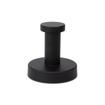 Un élégant butoir de porte cylindrique en métal noir avec une base ronde et un dessus plat de yessential.fr - un complément idéal avec votre ensemble WC Xavo Black ou d'autres accessoires de salle de bain noir mat. Photographié sur un fond blanc.