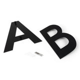 Deux grandes lettres plates Adamo Black 15 cm A et B de yessential.fr reposent sur une surface blanche avec des vis et des chevilles de fixation murale - parfaites comme numéro de maison élégant en acier inoxydable noir pour votre maison.