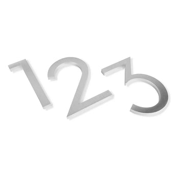 Trois chiffres métalliques (1, 2 et 3) sont placés en diagonale sur un fond blanc. Chaque numéro de maison Milano de 15 cm en acier inoxydable de yessential.fr a un design élégant avec une finition brossée pour un look élégant.