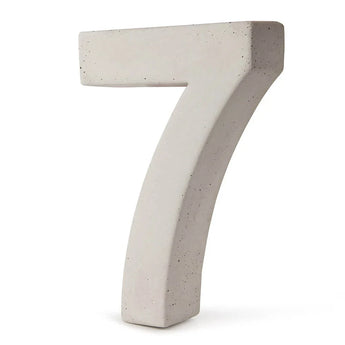 Un grand numéro 7 tridimensionnel en béton gris clair se dresse sur un fond blanc - c'est le numéro de maison Enrico en béton de 30 cm de yessential.fr.