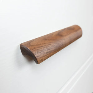 Un gros plan des poignées Lucasso Walnut de yessential.fr, présentant un design lisse et incurvé sur une façade de tiroir blanche - idéales pour un décor naturel.