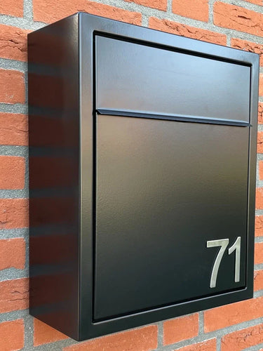 Une boîte aux lettres en métal noir portant le numéro 71, avec les numéros Animo en acier inoxydable de 5 cm (sans perçage) yessential.fr, est montée sur un mur de briques rouges.